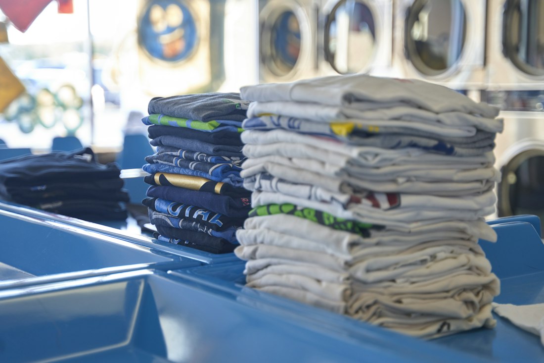 Piles de t-shirts propres et pliés dans une laverie